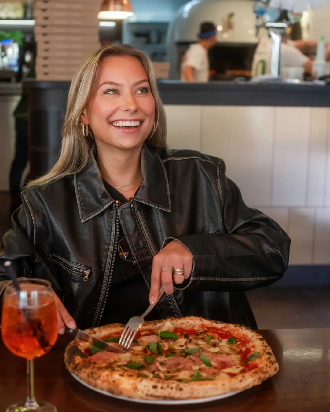 Gast genießt Pizza und Aperol