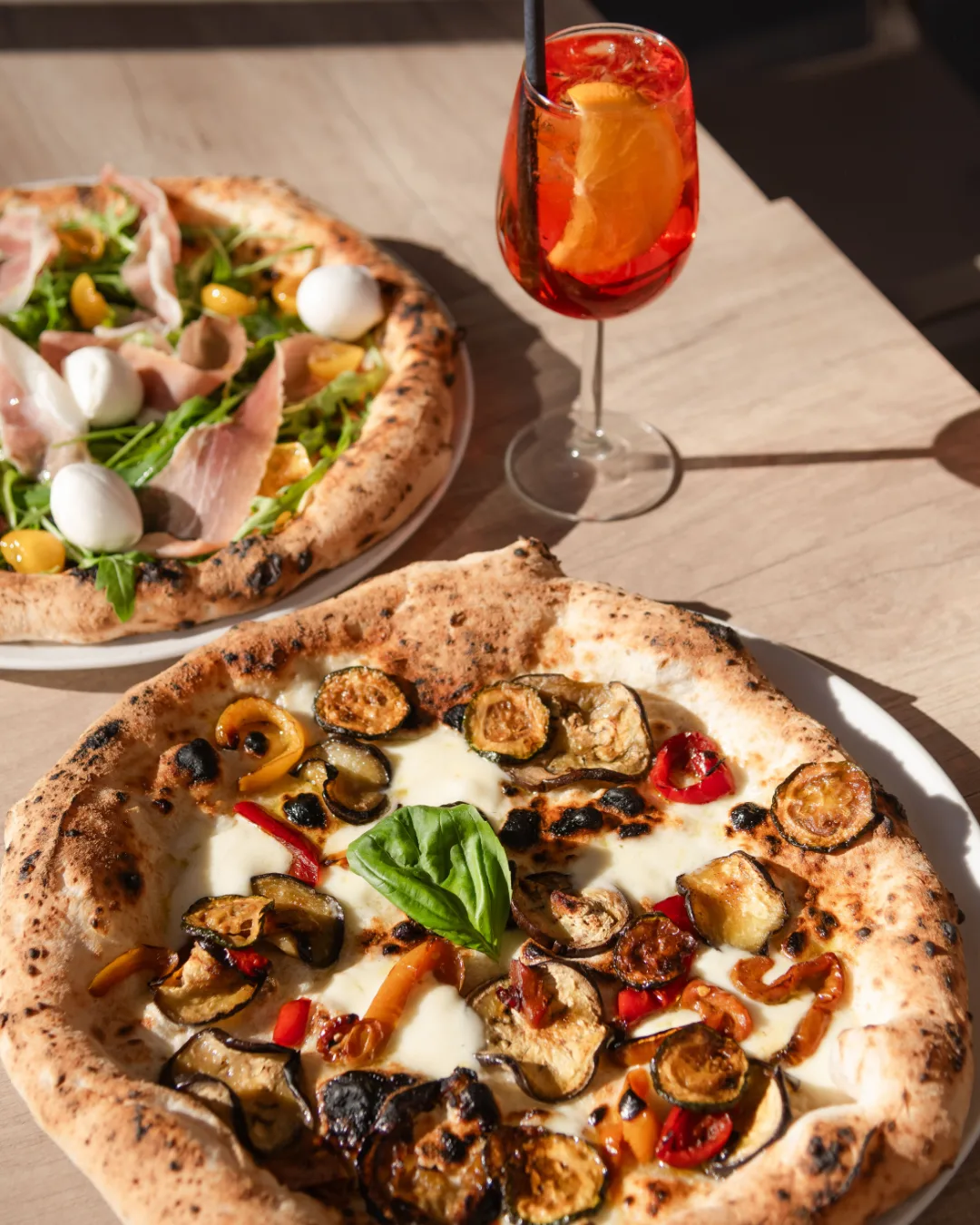 Zwei Pizzen und Aperol Spritz auf dem Tisch