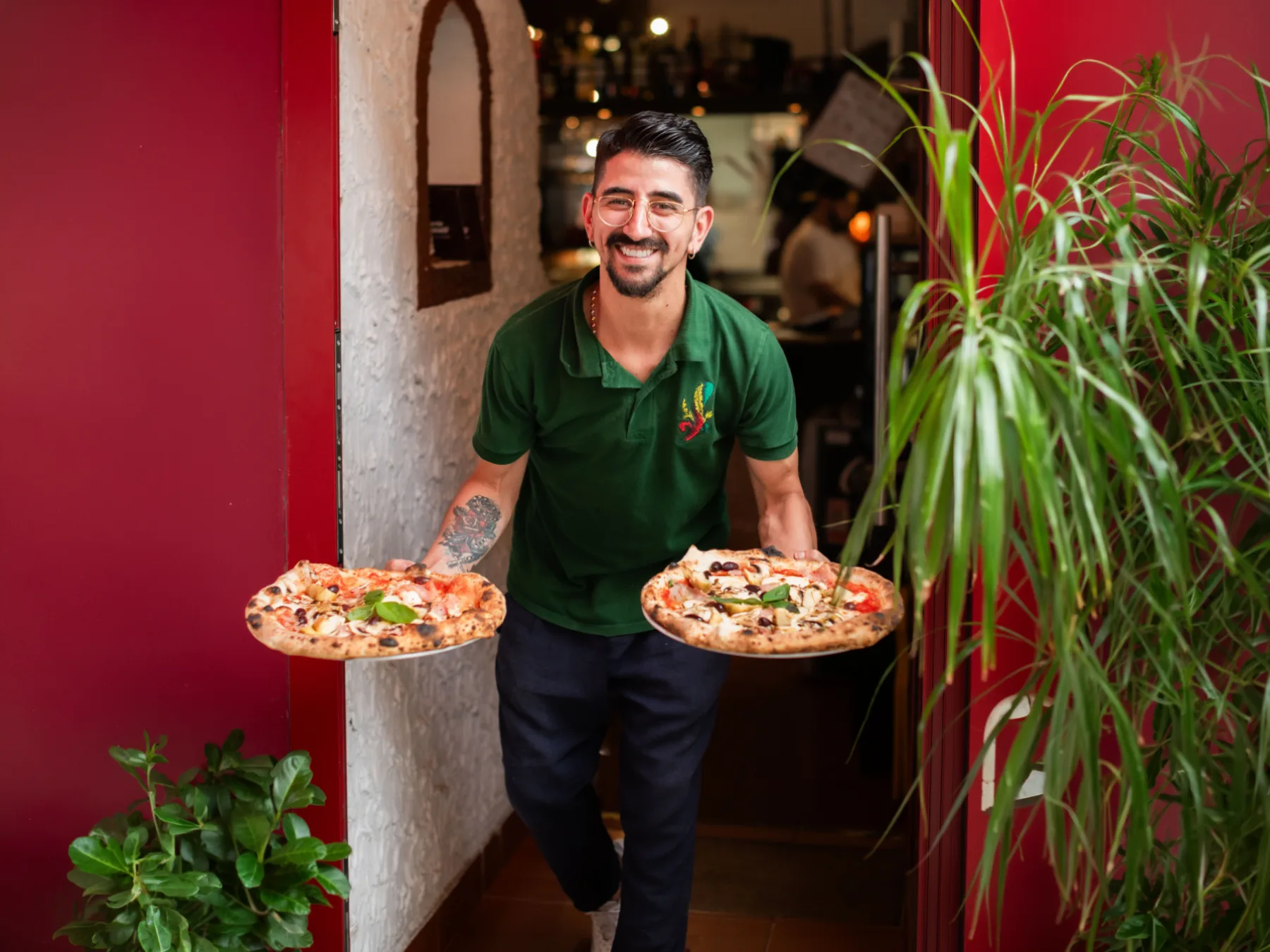 Pizzaiolo mit zwei Pizzen im Eingang der Pizzeria
